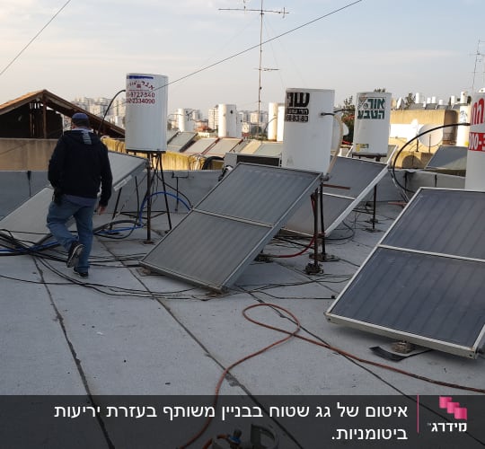 אדם על גג עם קולטי שמש ודודי מים